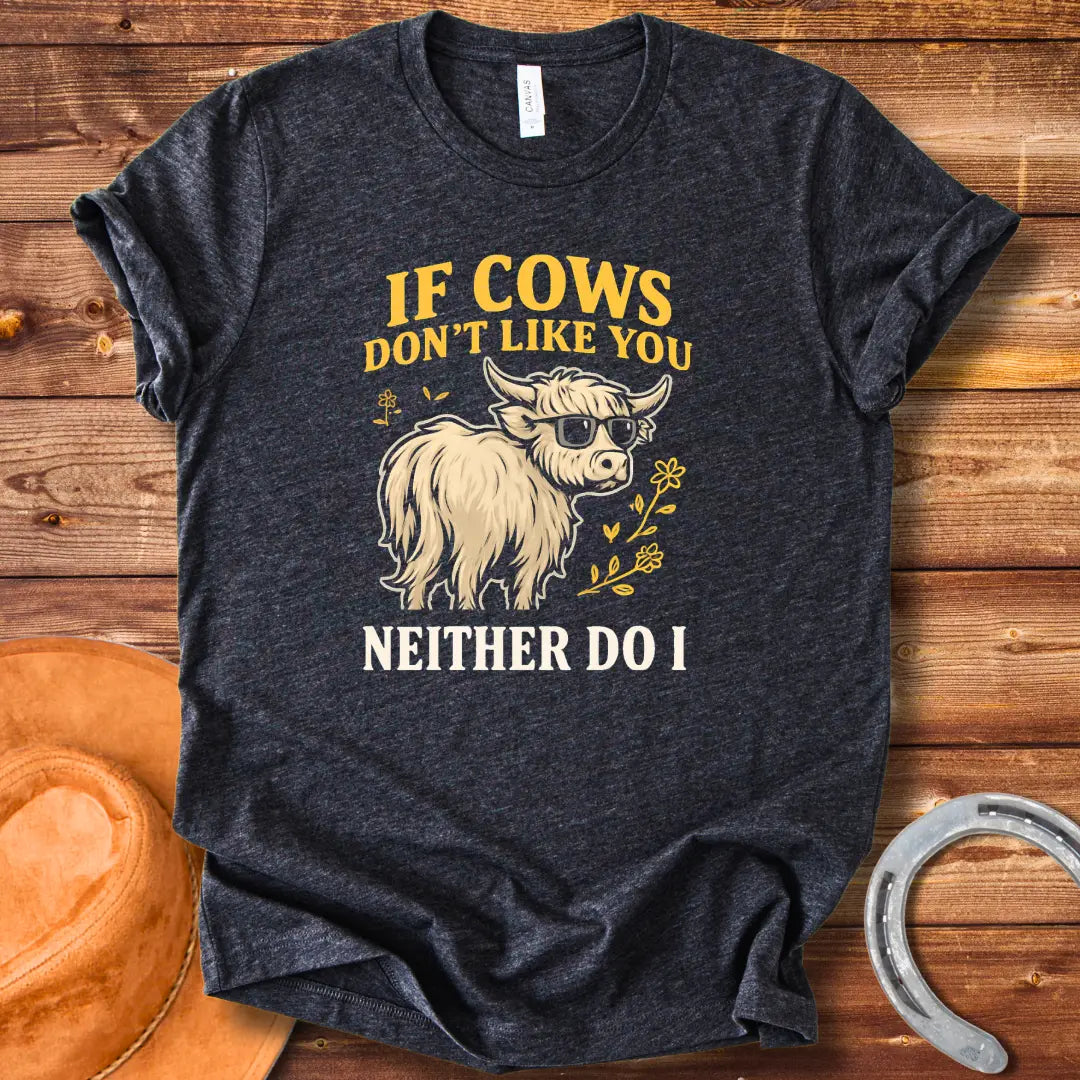 T-shirt design featuring a cool cow wearing sunglasses with the text 'If Cows Don't Like You Neither Do I' in brown and blue font on a black background.