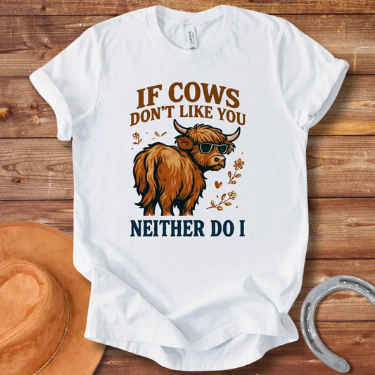 T-shirt design featuring a cool cow wearing sunglasses with the text 'If Cows Don't Like You Neither Do I' in brown and blue font on a black background.