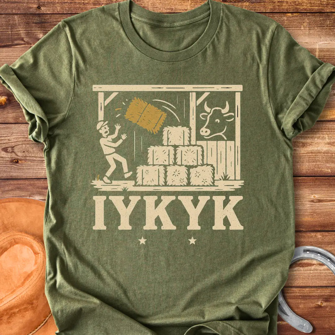 Funny t-shirt design featuring a person surprised by falling hay with a cow watching in the background.
