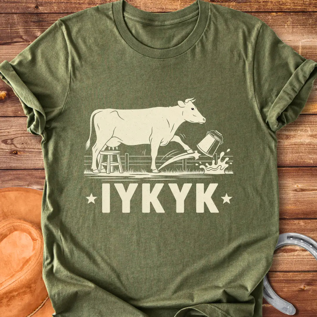 Illustration of a cow kicking a bucket, with the words 'IYKYK' and a farm scene background.