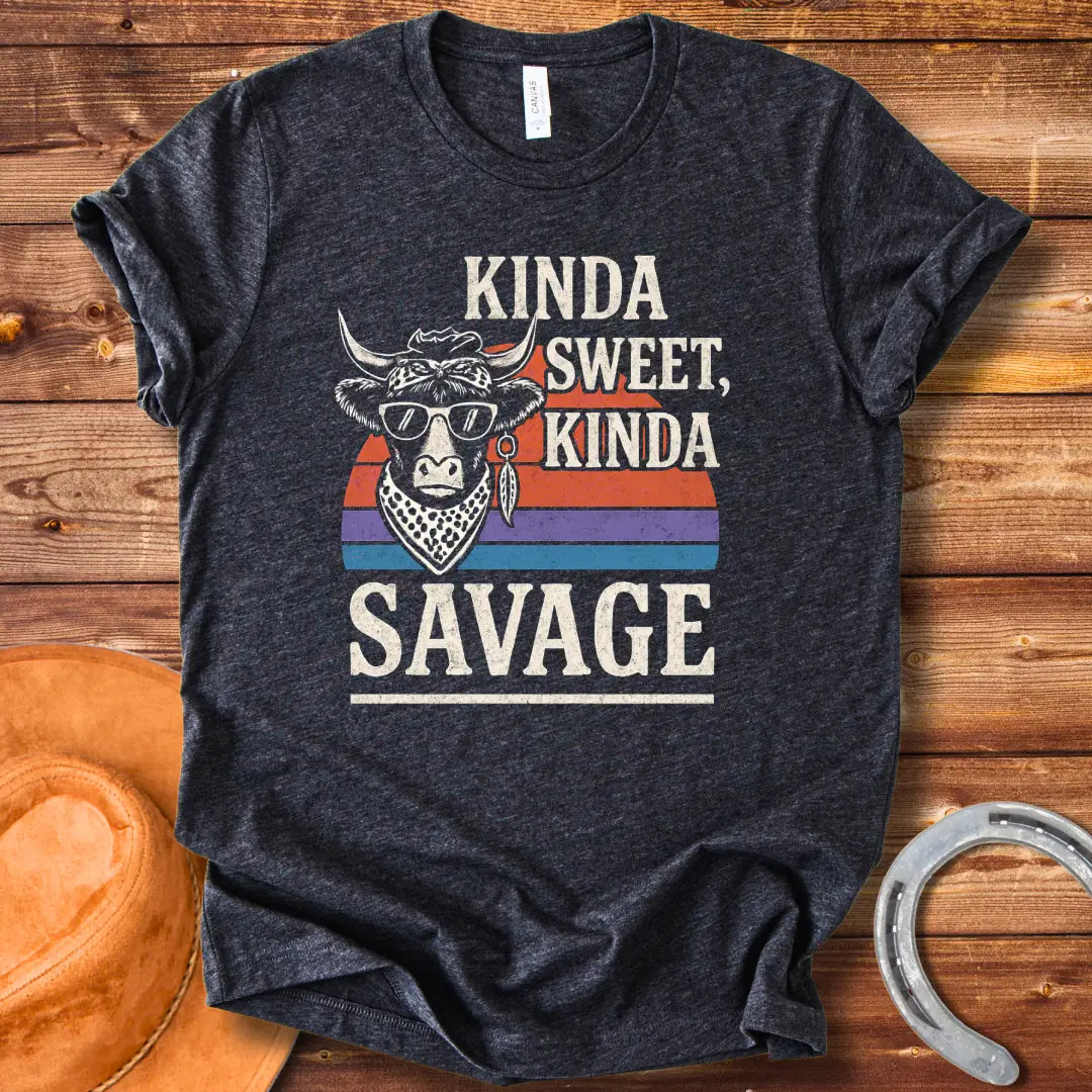 Vintage t-shirt featuring a cool cow wearing sunglasses and a bandana with the text 'Kinda Sweet Kinda Savage' over a retro sunset background.