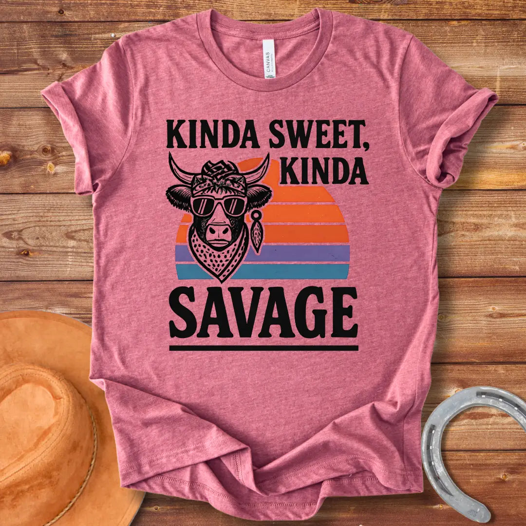Vintage t-shirt featuring a cool cow wearing sunglasses and a bandana with the text 'Kinda Sweet Kinda Savage' over a retro sunset background.