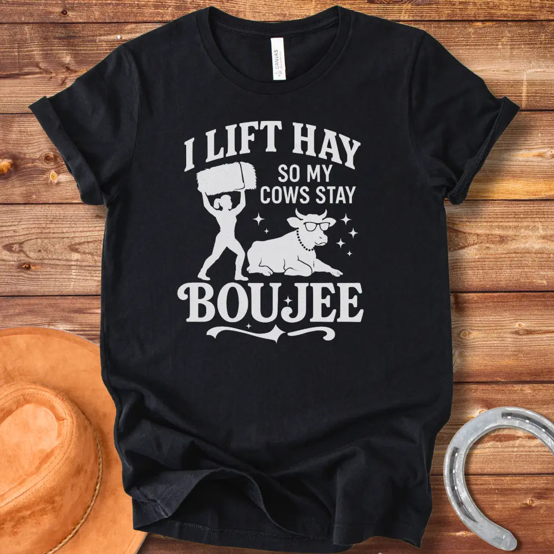 A silhouette design of a woman lifting a bale of hay and a cow wearing sunglasses and a pearl necklace. Text reads 'I lift hay so my cows stay boujee'.