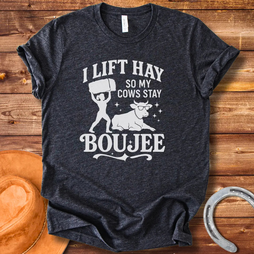 A silhouette design of a woman lifting a bale of hay and a cow wearing sunglasses and a pearl necklace. Text reads 'I lift hay so my cows stay boujee'.