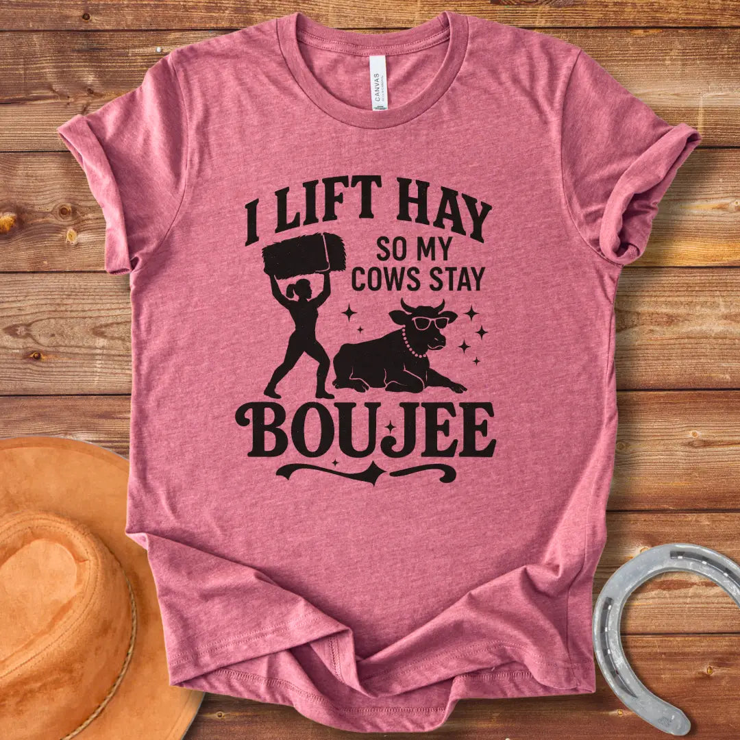 A silhouette design of a woman lifting a bale of hay and a cow wearing sunglasses and a pearl necklace. Text reads 'I lift hay so my cows stay boujee'.