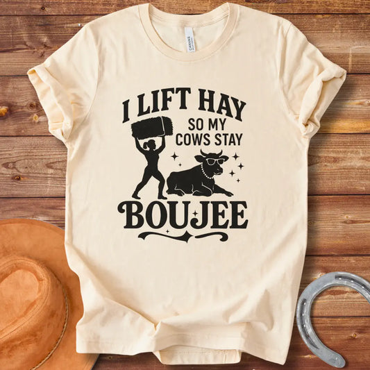 A silhouette design of a woman lifting a bale of hay and a cow wearing sunglasses and a pearl necklace. Text reads 'I lift hay so my cows stay boujee'.