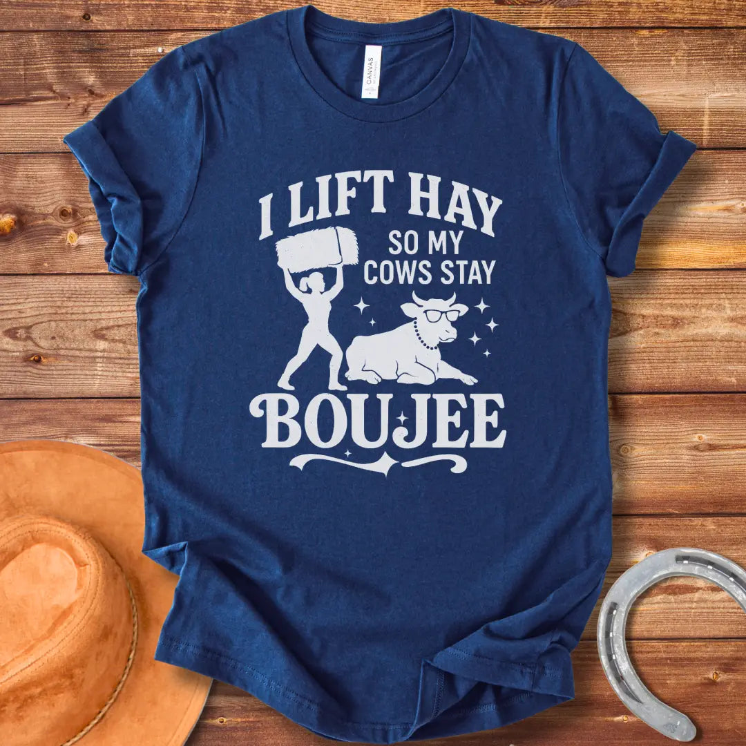 A silhouette design of a woman lifting a bale of hay and a cow wearing sunglasses and a pearl necklace. Text reads 'I lift hay so my cows stay boujee'.