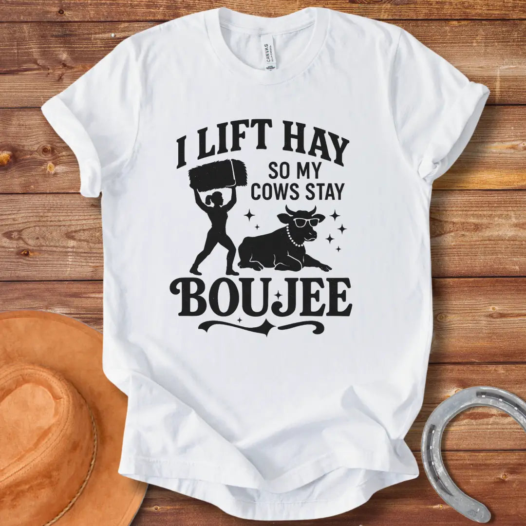 A silhouette design of a woman lifting a bale of hay and a cow wearing sunglasses and a pearl necklace. Text reads 'I lift hay so my cows stay boujee'.