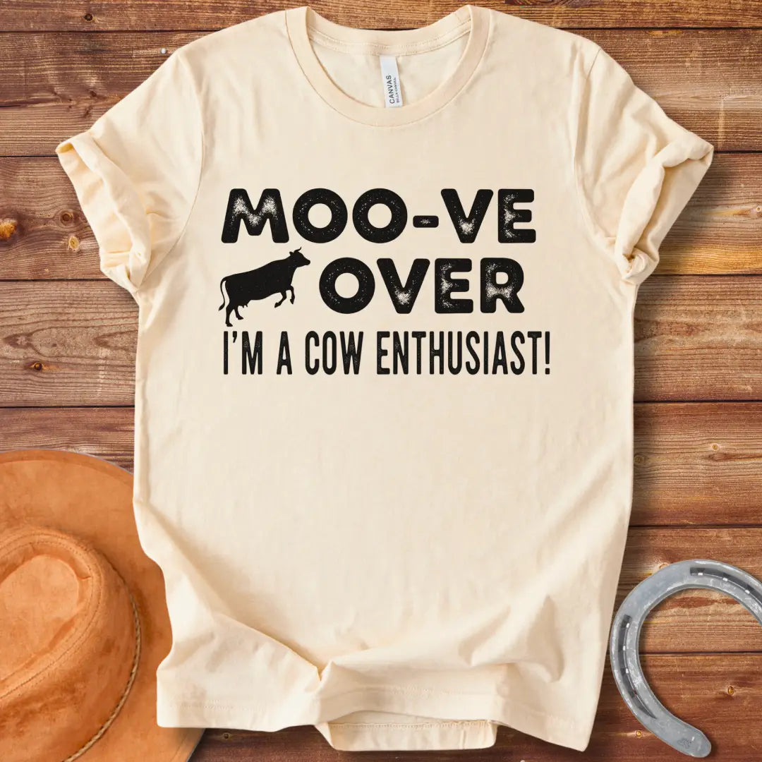 A black and white graphic tee design that says 'Moo-ve Over' with a silhouette of a cow and 'I'm a Cow Enthusiast!' below.