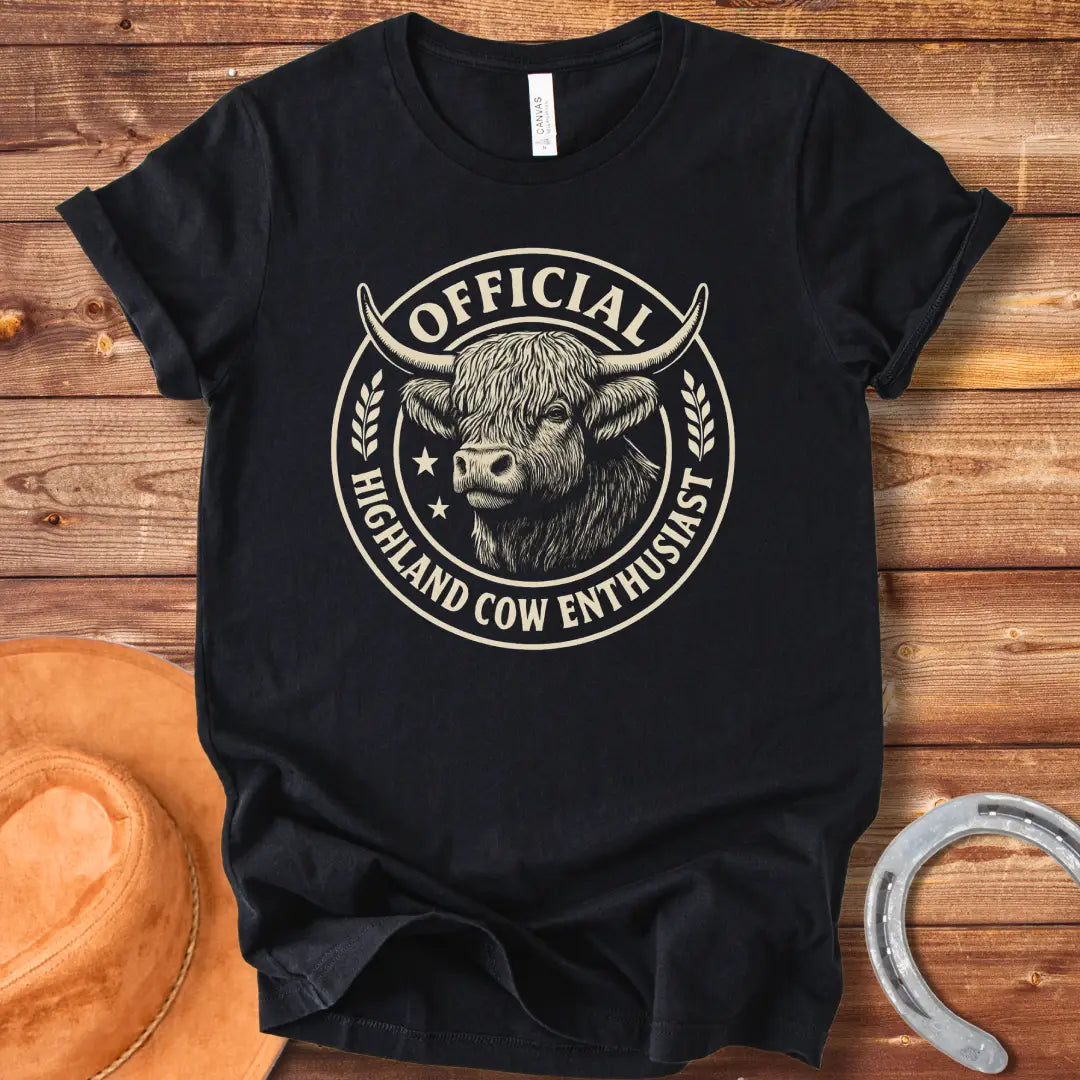 Official Highland Cow Enthusiast T-Shirt design featuring a detailed illustration of a Highland cow's head within a circular emblem with the words 'Official Highland Cow Enthusiast' written on it.