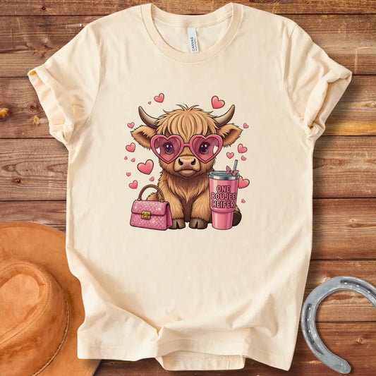 Illustration of a fluffy cow wearing heart-shaped sunglasses and holding a pink drink and purse that says 'One Boujee Heifer' with pink hearts surrounding it.