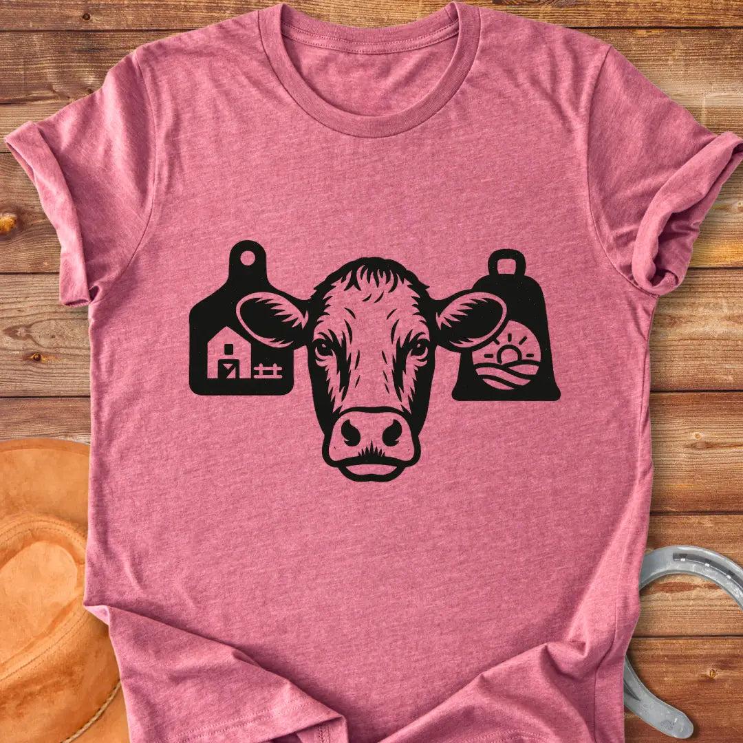 Black and white silhouette of a cow's head with bell tags, one showing a farm and the other with a landscape with sun