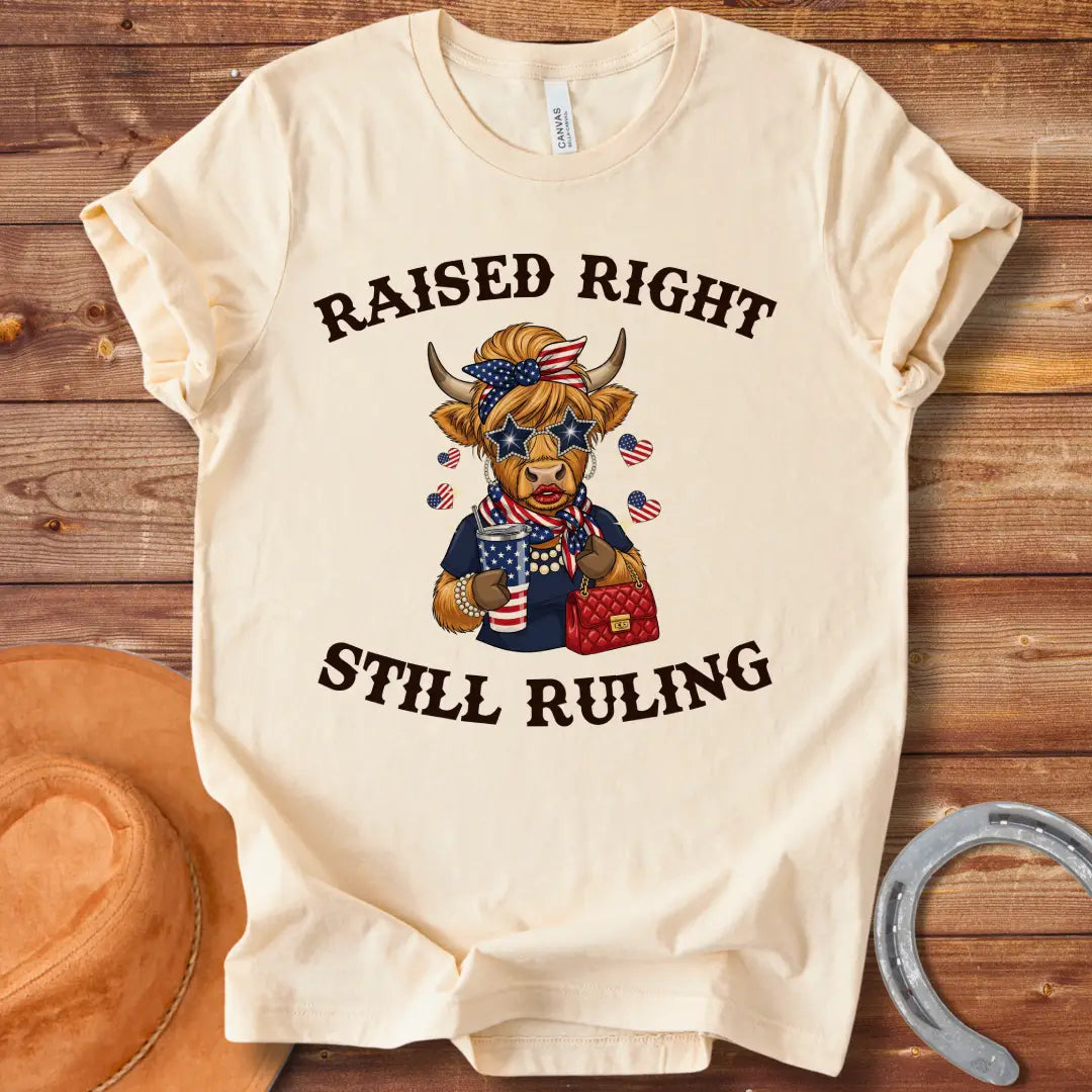 Stylish cow wearing star sunglasses and a patriotic scarf, holding a drink and purse, with the text 'Raised Right Still Ruling' above.