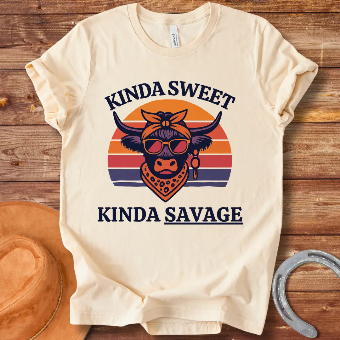 Retro t-shirt with a cool cow graphic, sunglasses, bandana, and the words 'Kinda Sweet, Kinda Savage' in a sunset background.