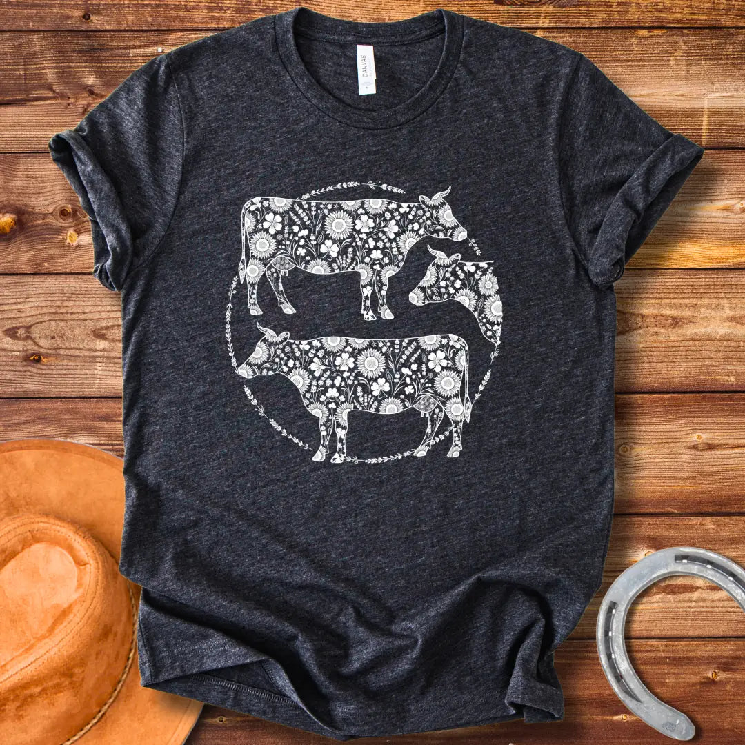 Black and white illustration of three cows with floral patterns within a circle.