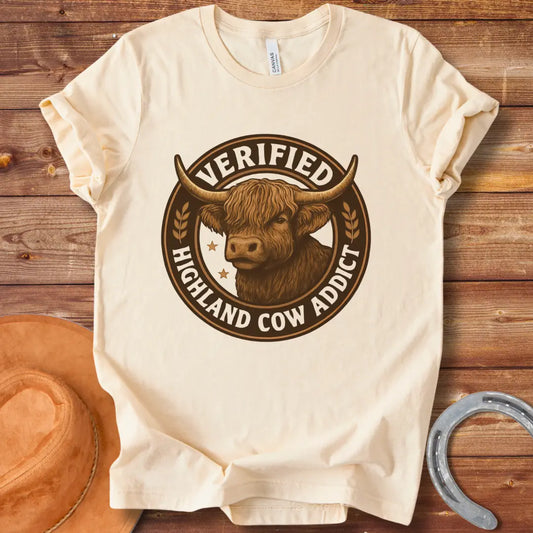 Verified Highland Cow Addict T-Shirt featuring a detailed illustration of a Highland cow in a circular design with the words 'Verified Highland Cow Addict' 