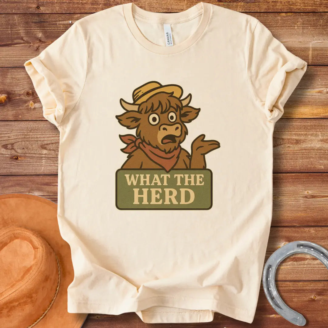 Funny t-shirt design featuring a surprised cow with the words 'What The Herd?' on a sign.
