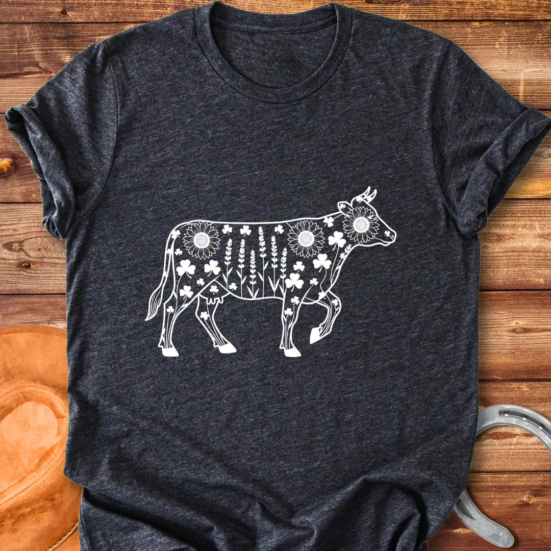 Line art of a cow filled with wildflowers, including sunflowers, lavender and clovers, on a black background.