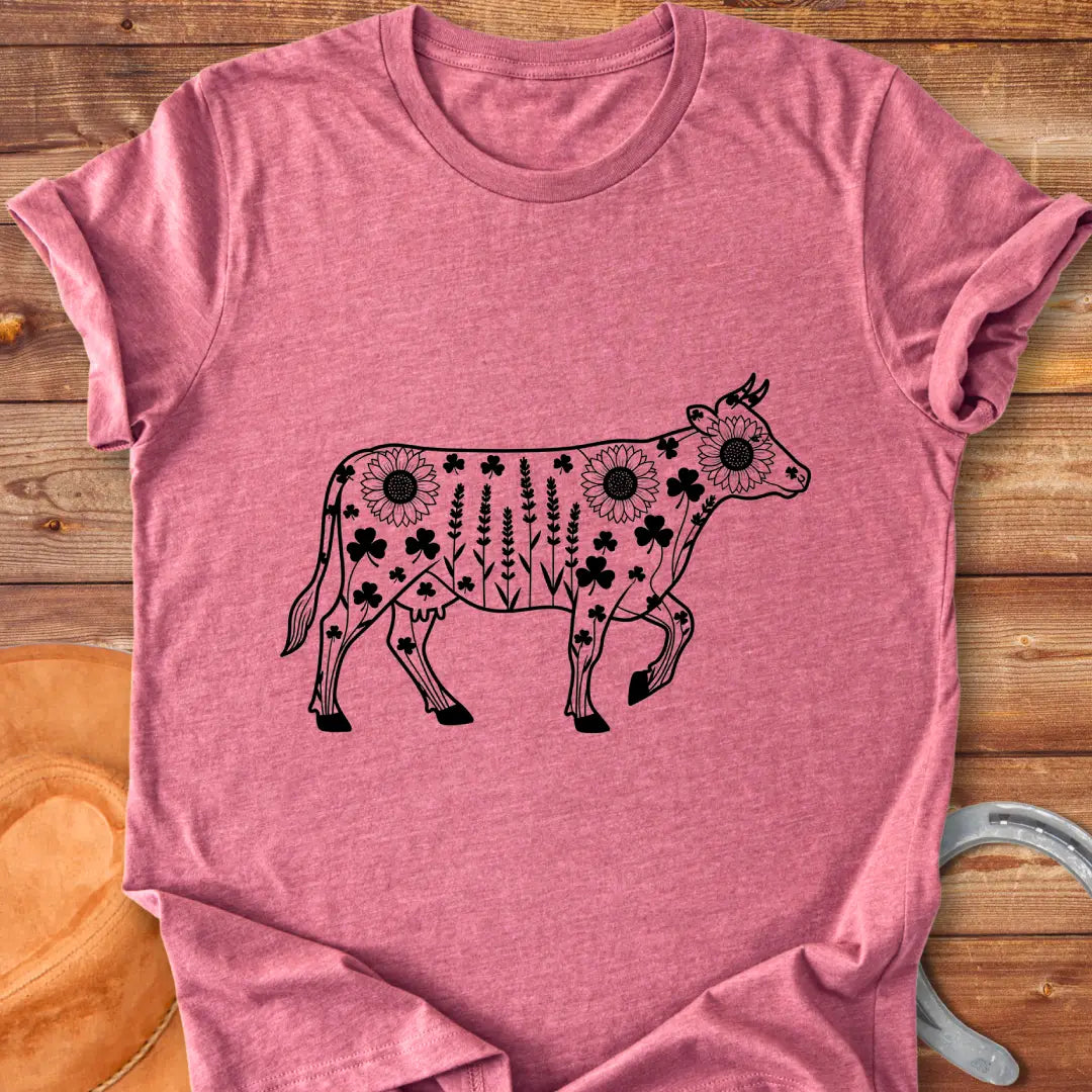 Line art of a cow filled with wildflowers, including sunflowers, lavender and clovers, on a black background.
