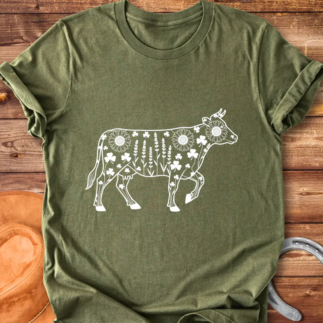 Line art of a cow filled with wildflowers, including sunflowers, lavender and clovers, on a black background.